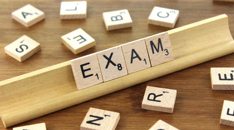 Scrabble tiles spelling out "EXAM"